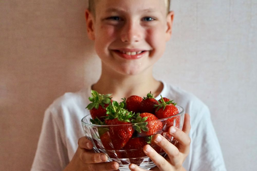 Child holding strawberries to make infused water as a summer treat