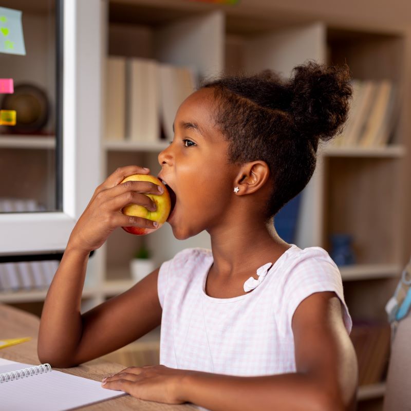 girl eating late summer fruit apple